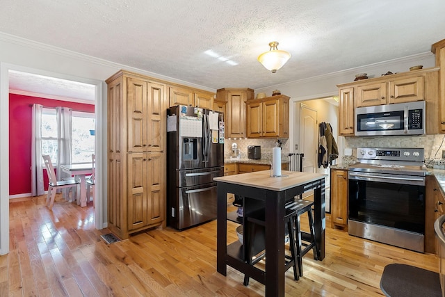 kitchen featuring light wood finished floors, visible vents, tasteful backsplash, crown molding, and stainless steel appliances