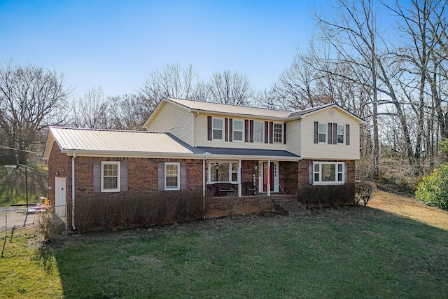 traditional home with a front yard, fence, brick siding, and metal roof