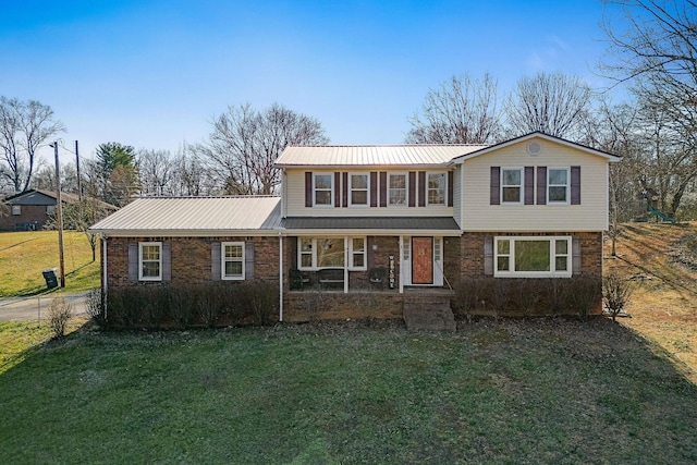 traditional-style home with brick siding, metal roof, a front lawn, and fence