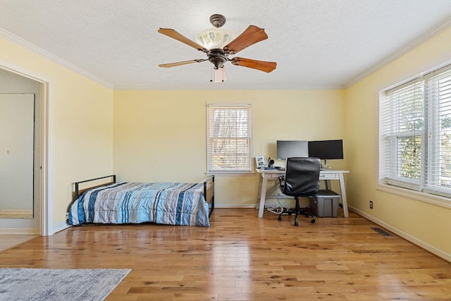 bedroom with crown molding, multiple windows, visible vents, and wood-type flooring