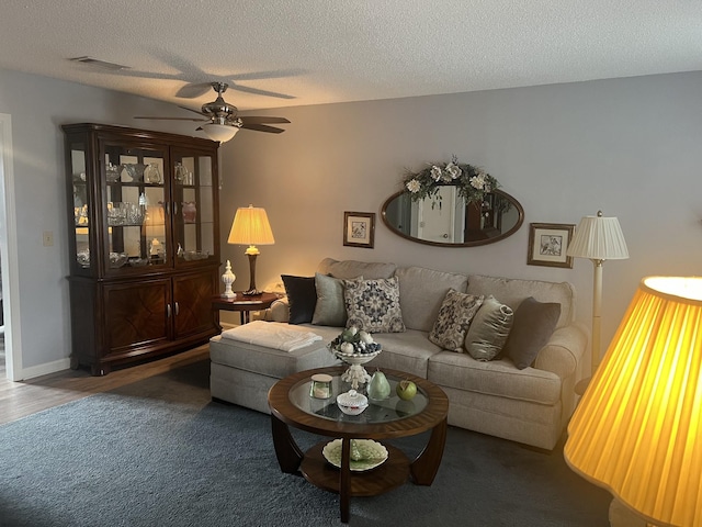 living area with visible vents, baseboards, wood finished floors, a textured ceiling, and a ceiling fan