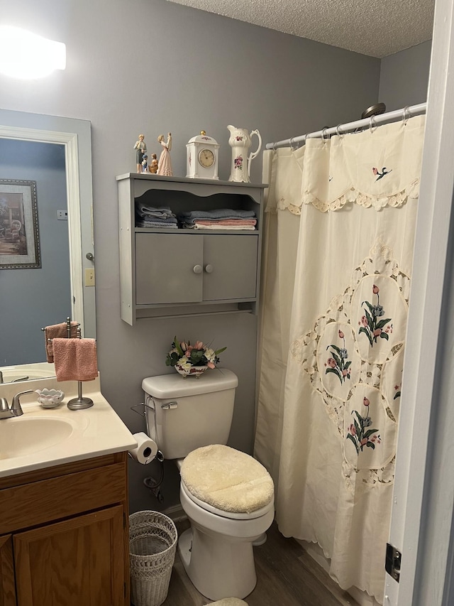 full bathroom with toilet, a shower with shower curtain, vanity, wood finished floors, and a textured ceiling