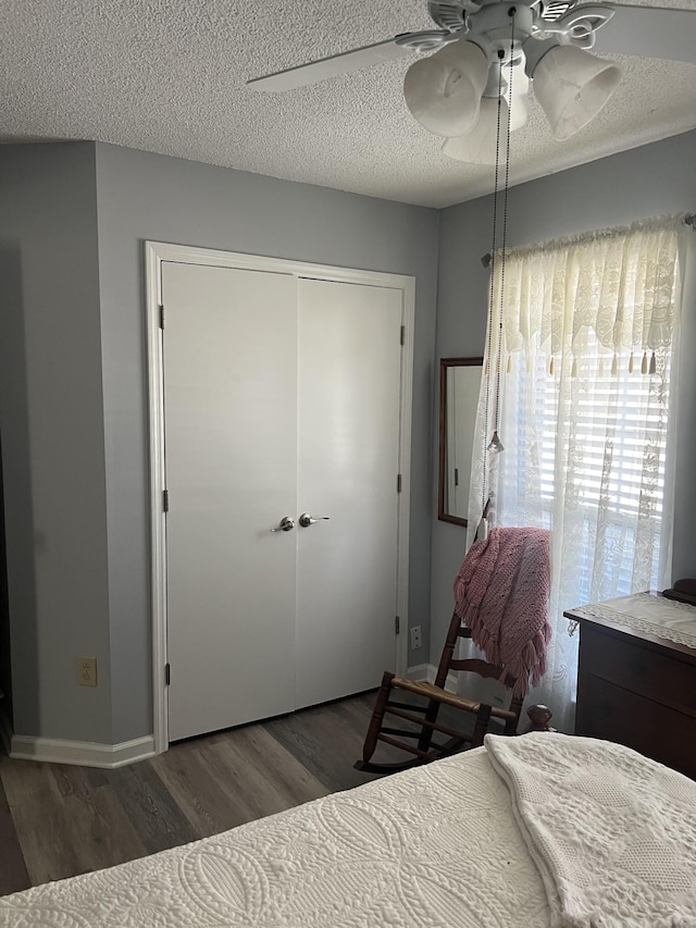 bedroom with wood finished floors, baseboards, a closet, and a textured ceiling