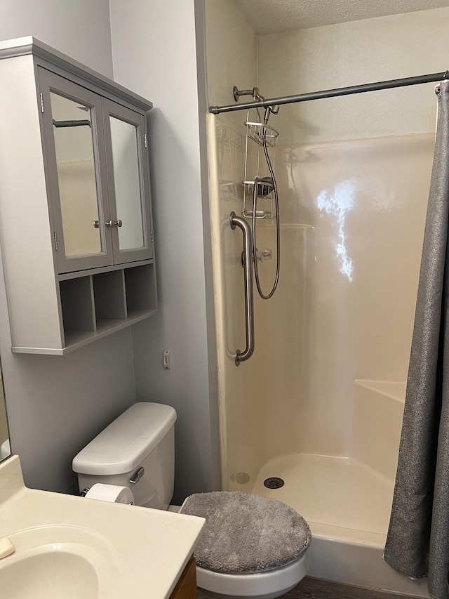 bathroom featuring toilet, a stall shower, and vanity