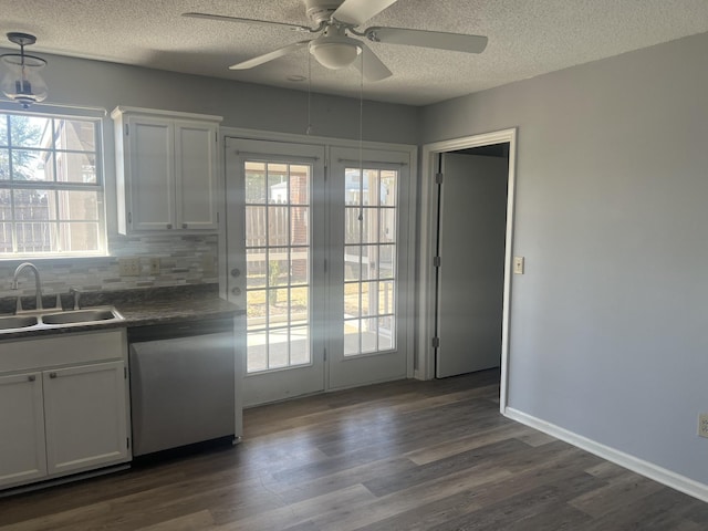 kitchen with dishwasher, dark countertops, white cabinets, and a sink