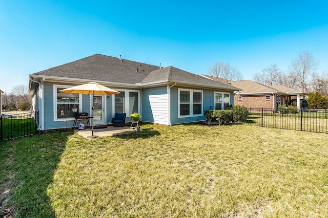 back of property with a lawn, roof with shingles, a fenced backyard, and a patio area