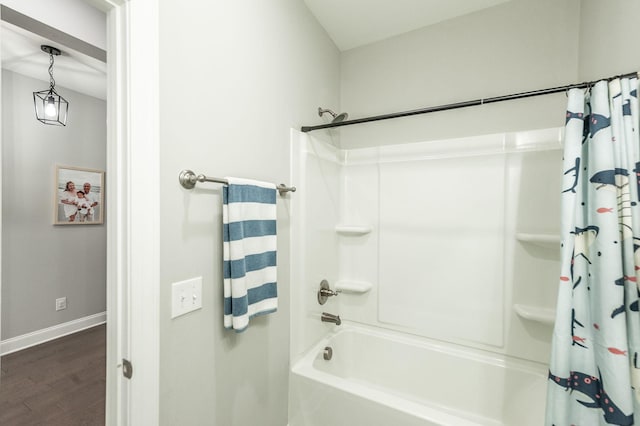 bathroom with shower / tub combo, wood finished floors, and baseboards