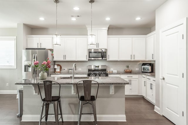 kitchen featuring visible vents, a center island with sink, stainless steel appliances, white cabinetry, and a sink