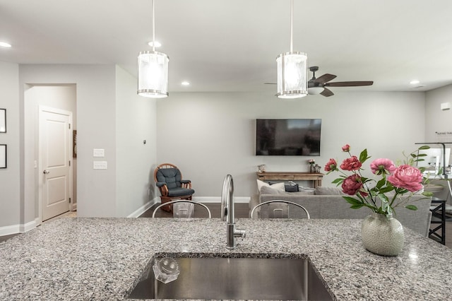 kitchen featuring hanging light fixtures, recessed lighting, stone countertops, and a sink