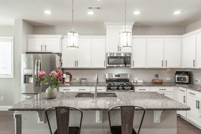 kitchen with a sink, visible vents, a kitchen breakfast bar, and appliances with stainless steel finishes