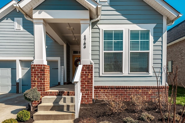 view of exterior entry with brick siding and driveway