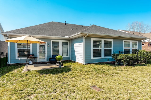 back of property featuring a lawn, a shingled roof, a patio, and fence