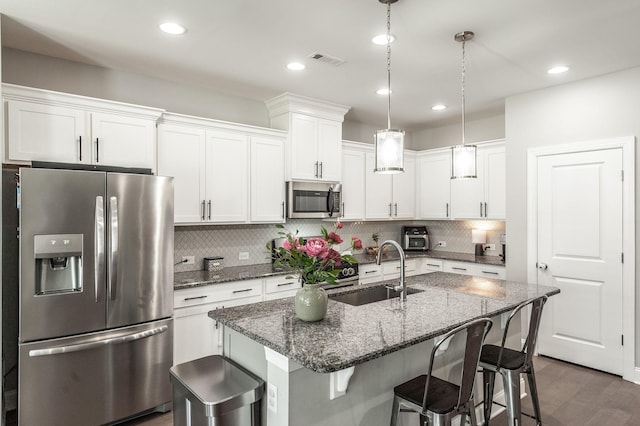 kitchen with visible vents, a kitchen bar, stainless steel appliances, white cabinetry, and a sink