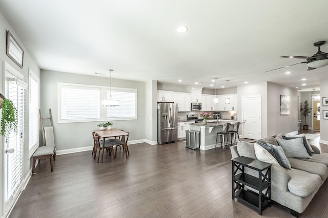 living area with recessed lighting, baseboards, a ceiling fan, and dark wood-style flooring