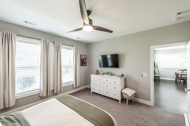 carpeted bedroom with visible vents, baseboards, and ceiling fan