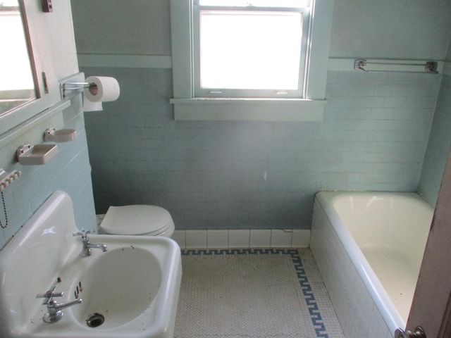 bathroom featuring tile patterned flooring, tile walls, toilet, and tiled bath