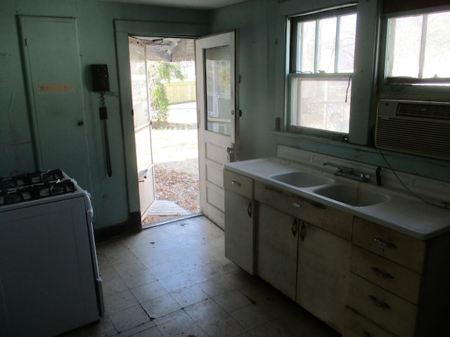 kitchen with range with gas cooktop, light floors, light countertops, cooling unit, and a sink