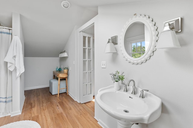 full bathroom featuring lofted ceiling, wood finished floors, baseboards, and a sink