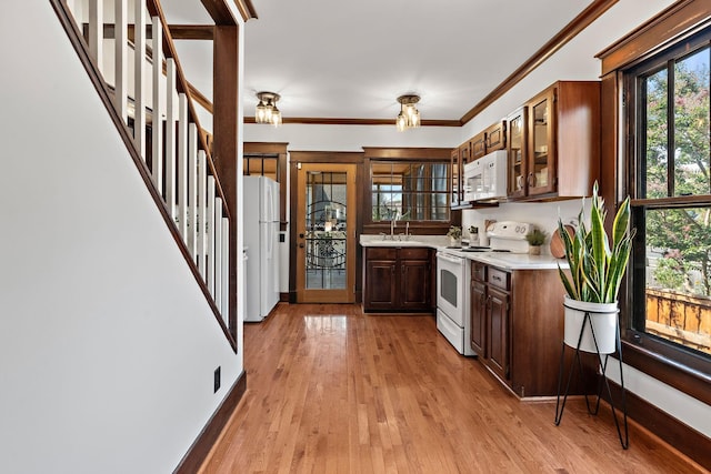 kitchen featuring white appliances, baseboards, light wood-style flooring, ornamental molding, and light countertops