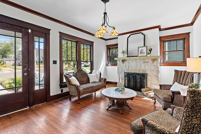 living area with hardwood / wood-style flooring, french doors, crown molding, a fireplace, and baseboards