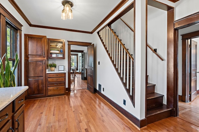 foyer with stairway, light wood-style flooring, and ornamental molding