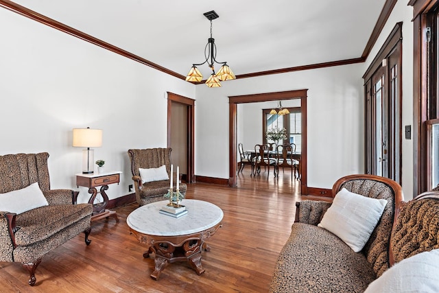 living room with crown molding, wood finished floors, baseboards, and a chandelier