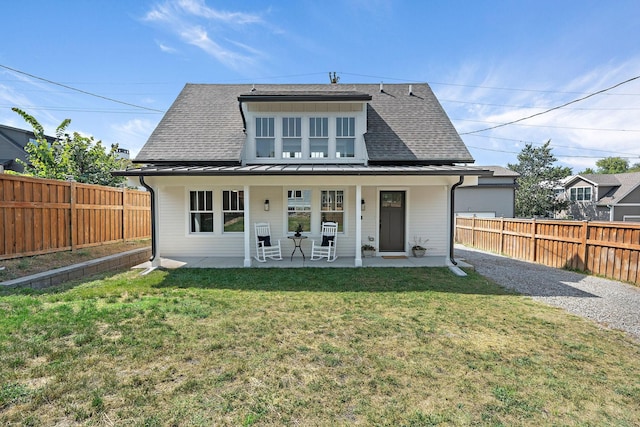 back of house with a fenced backyard, a shingled roof, and a yard