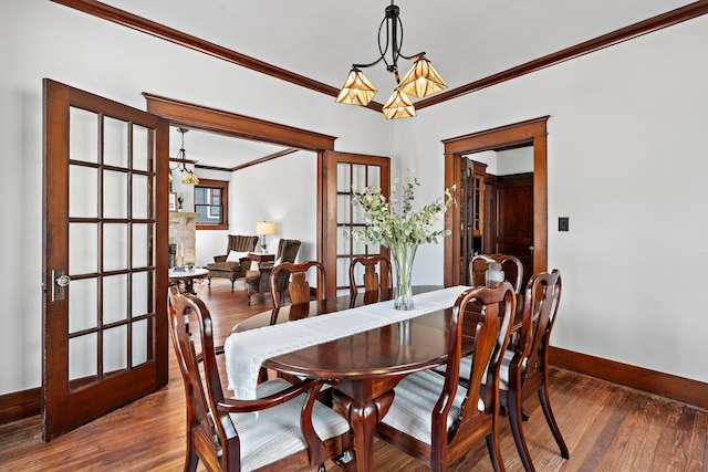 dining room with ornamental molding, an inviting chandelier, baseboards, and hardwood / wood-style floors