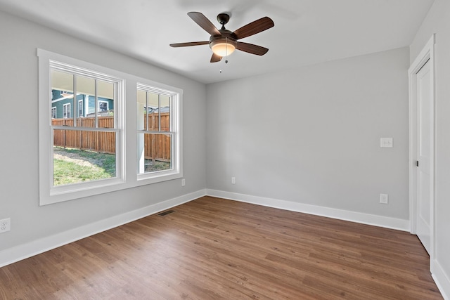 spare room with visible vents, wood finished floors, baseboards, and ceiling fan