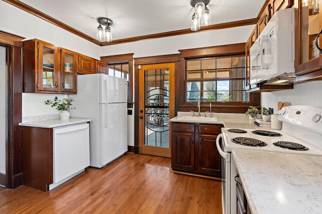 kitchen with white appliances, light wood-style flooring, a sink, glass insert cabinets, and crown molding