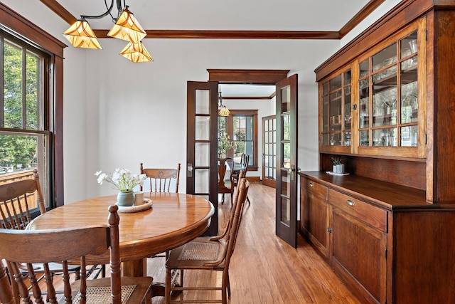 dining space with baseboards, french doors, light wood-style floors, and ornamental molding