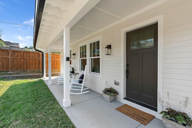 entrance to property with a yard, a porch, and fence