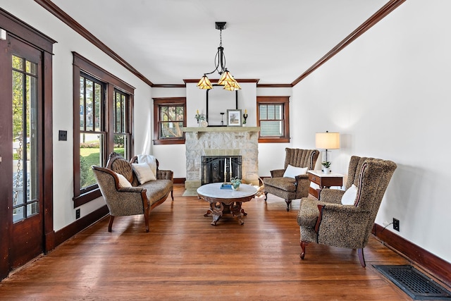 living area featuring visible vents, baseboards, a stone fireplace, and wood finished floors