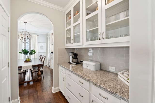 kitchen with tasteful backsplash, glass insert cabinets, dark wood-type flooring, and ornamental molding