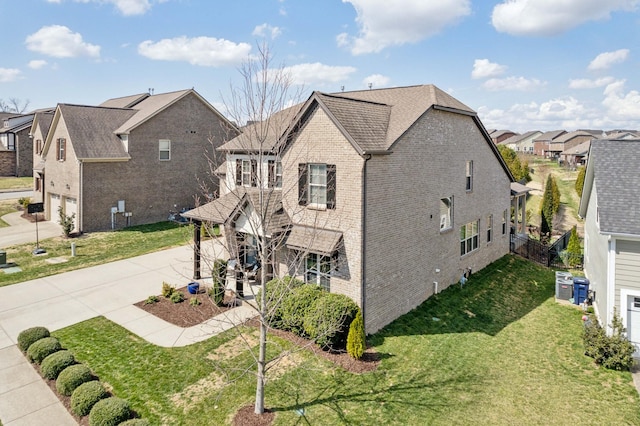 view of property exterior featuring a lawn, fence, a residential view, concrete driveway, and brick siding