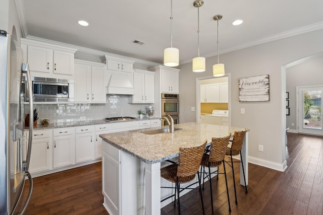 kitchen with visible vents, a sink, washing machine and dryer, stainless steel appliances, and custom exhaust hood