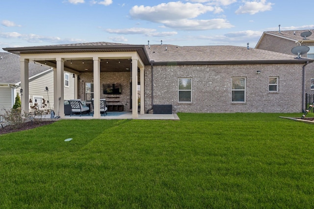 back of house with a patio area, a lawn, a shingled roof, and brick siding