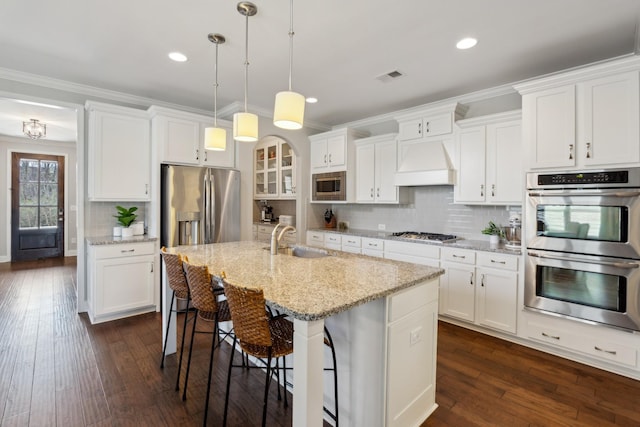 kitchen with a sink, dark wood finished floors, appliances with stainless steel finishes, crown molding, and custom exhaust hood