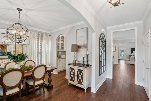 entrance foyer with arched walkways, a notable chandelier, dark wood finished floors, and ornamental molding