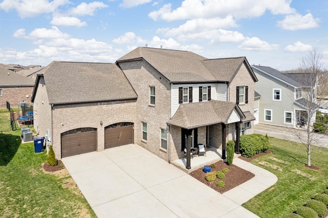 view of front of property featuring a front yard, concrete driveway, brick siding, and roof with shingles