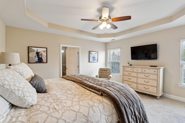 bedroom featuring a tray ceiling, baseboards, light colored carpet, and ceiling fan