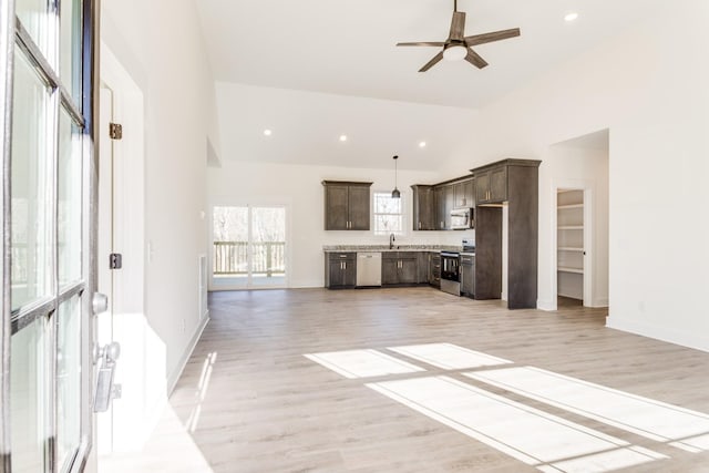 unfurnished living room featuring baseboards, high vaulted ceiling, light wood-style flooring, recessed lighting, and ceiling fan