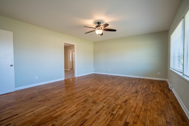 unfurnished room with baseboards, a ceiling fan, and dark wood-style flooring