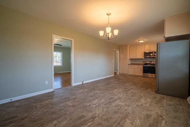 kitchen featuring baseboards, hanging light fixtures, white cabinets, appliances with stainless steel finishes, and a chandelier