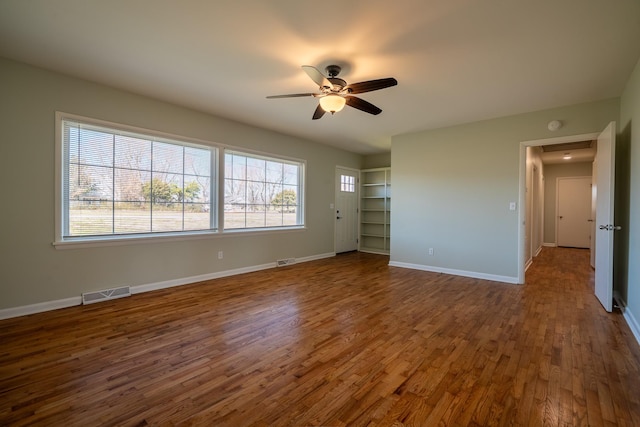 interior space featuring visible vents, a ceiling fan, baseboards, and wood finished floors