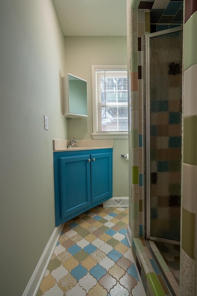 bathroom featuring a stall shower, vanity, and baseboards