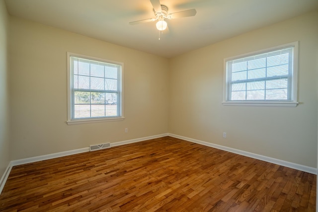 spare room with visible vents, ceiling fan, baseboards, and wood finished floors