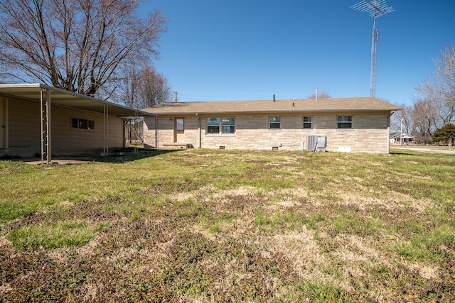 back of property with stone siding and a lawn