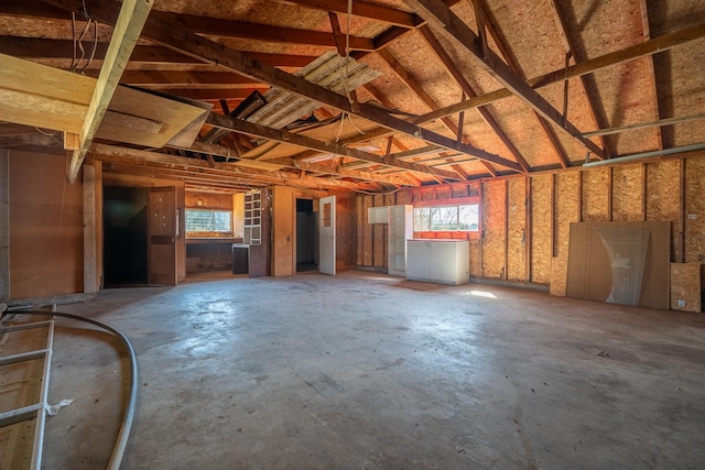 misc room with lofted ceiling, concrete floors, and a garage