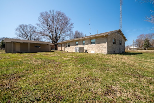 back of property featuring stone siding and a yard